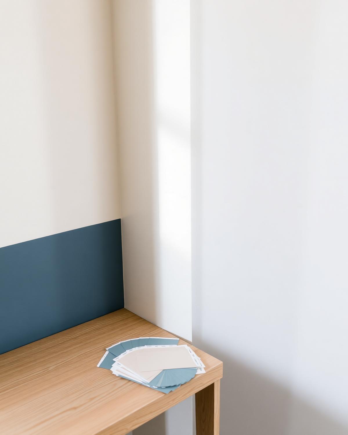 Kleurstalen op een houten tafel naast een blauwe muur